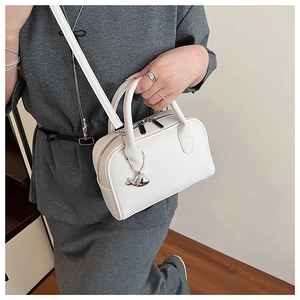 Close-up of white lychee pattern leather handbag with silver dolphin charm detail