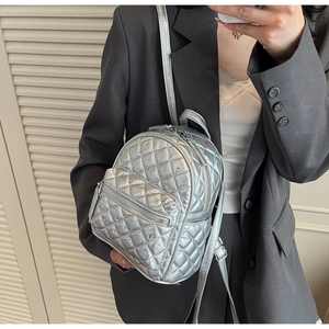 Close-up of a silver quilted mini backpack featuring rhinestone accents and metal texture