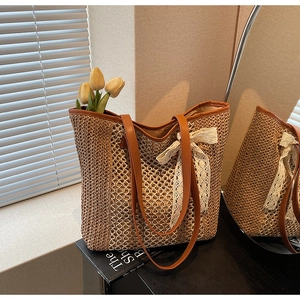 Détail du sac cabas en paille tressée avec anses en cuir marron et nœud en dentelle blanche