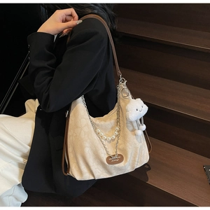 Detail of canvas hobo bag with pearl chain, silver hardware, and plush cloud charm