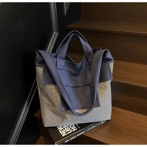 Close-up of a large capacity striped canvas tote bag with dual straps on wooden stairs