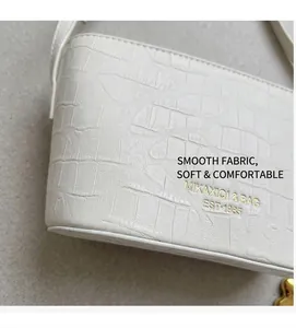Close-up of white crocodile pattern texture and gold brand logo on the bucket bag