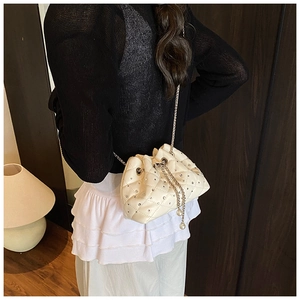 Detail of quilted bucket bag with silver studs, chain drawstring and pearl charms