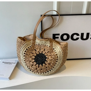 Detail of sunflower pattern straw tote bag with brown leather straps and stitching