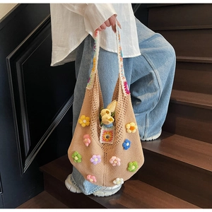 Detail of bohemian knit tote bag featuring colorful 3D crochet flowers on beige fabric