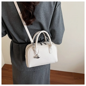 Detail of white lychee leather bowling bag with silver whale charm and cross-body strap
