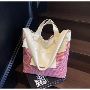 Detail of red and white checkered canvas tote bag with cream straps on wooden steps