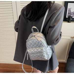 Detail of silver quilted mini backpack with rhinestone studs worn by model in soft light