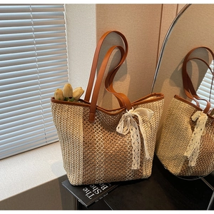 Détail du sac cabas en paille tissée avec nœud en dentelle blanche et anse en cuir