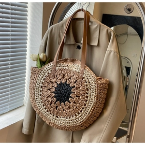 Detail of the multi-colored sunflower weave pattern on a round straw tote beach bag