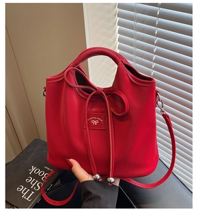 Detailed view of red bucket bag with bow drawstring and adjustable shoulder strap