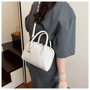 Detail of white lychee leather handbag with silver elephant charm and slim strap