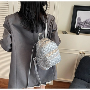 Detail of silver quilted mini backpack with metallic finish shown on model for size