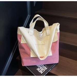 Close-up of red gingham canvas tote bag with multi-pockets on artistic background