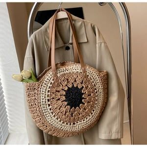 Detailed view of hand-woven circular straw tote bag with sunflower pattern and leather handles