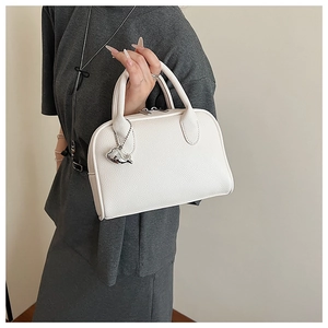Detail of white litchi pattern leather handbag with silver dolphin charm and dual zippers