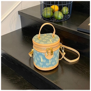 Detailed close-up of blue denim bucket bag with leather trim and gold metal zippers