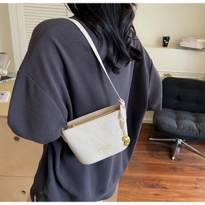 Detail of cream bucket bag with crocodile embossing shown on shoulder for scale