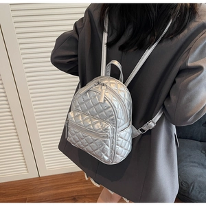 Close-up of silver quilted mini backpack with rhinestone details on a model