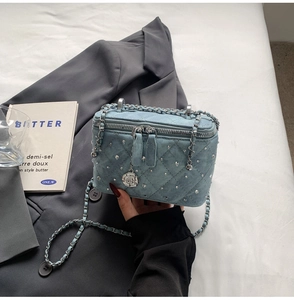 Detailed macro shot of blue denim quilted box bag with silver studs and chain strap
