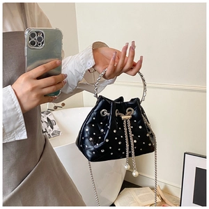 Detail of black rhinestone bucket bag with metal ring handle and pearl drawstring charms