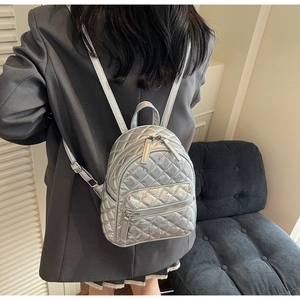 Detail of silver quilted mini backpack with rhinestone accents on a female model