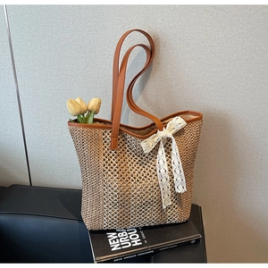 Détail du sac cabas en paille tressée avec anses en cuir marron et nœud en dentelle