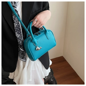 Detail of turquoise boston bag with silver whale charm and pebble leather texture