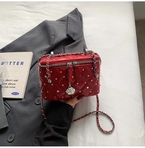 Detail of red quilted leather box bag with silver studs and camellia charm