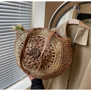 Detailed close-up of circular straw woven tote with leather straps and geometric pattern