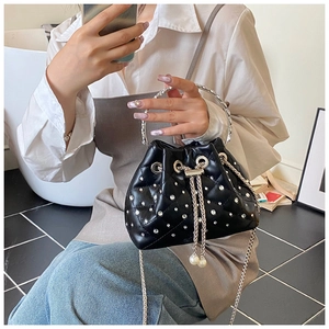 Detail of black quilted bucket bag featuring crystals, silver handle, and pearl drawstring
