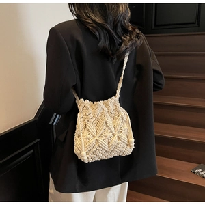 Détail du sac seau en macramé beige tissé main avec perles en bois et texture géométrique