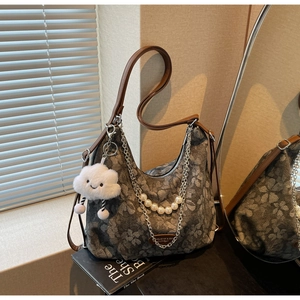 Detail of taupe floral tote bag featuring pearl chain strap and plush cloud charm