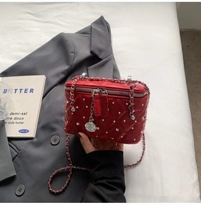Close-up of red quilted box bag with silver beads and camellia charm detail