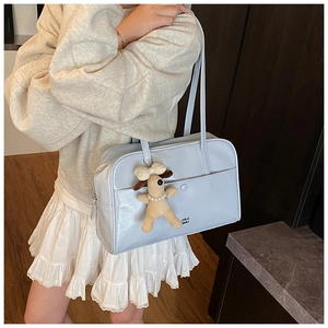 Detail view of a blue retro bowling bag with a cute plush puppy pendant and metal snap