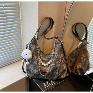 Detail of floral hobo bag with pearl chain decoration and brown leather handles