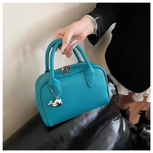 Detail of cyan lychee grain leather handbag with dual zippers and silver whale charm