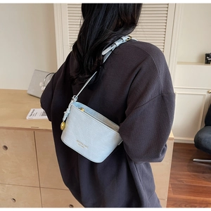 Close-up of light blue crocodile embossed mini bucket bag with gold ball charm detail