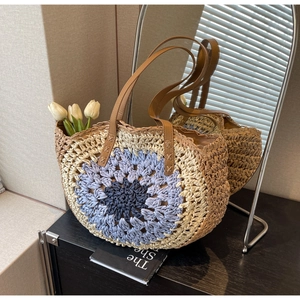Detail of multi-colored round woven straw bag with leather handles and interior lining