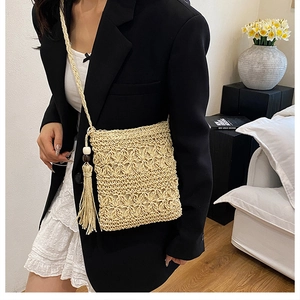 Close-up of handmade straw crossbody bag with floral hollow pattern and tassels