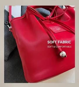 Detail of red leather bucket bag with brand logo patch and silver drawstring beads