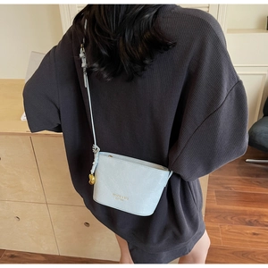 Detail of light blue crocodile pattern crossbody bucket bag worn over the shoulder