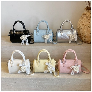 Multiple colorful small Boston handbags in pink, yellow, silver, and blue on stone steps