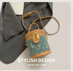 Detailed view of blue denim bucket bag with brown leather trim and golden zippers