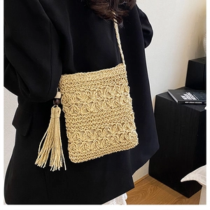Detail of beige hand-woven straw crossbody bag with floral texture and long tassels