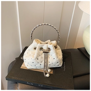 Close-up of quilted bucket bag with rhinestone circular handle and pearl tassel