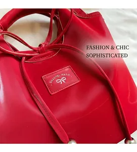 Detailed view of red glossy tote bag featuring drawstring closure and bow logo