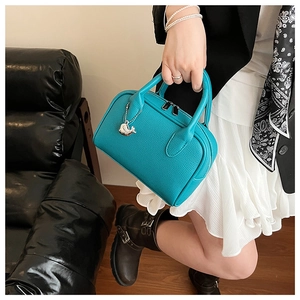 Detail of blue leather boston bag with a silver whale charm and dual zipper closure