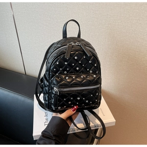 Detail of black quilted mini backpack featuring sparkling rhinestones and silver zippers