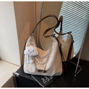 Detail of cream canvas shoulder bag with plush cloud charm and pearl chain decoration